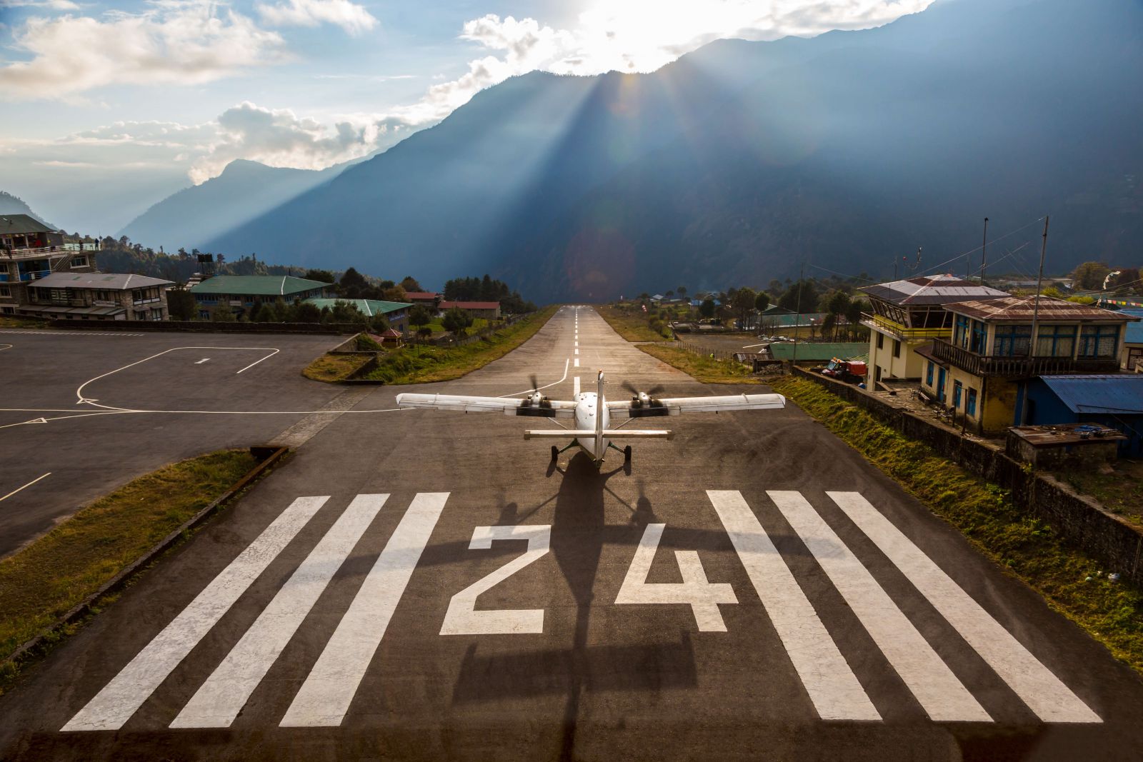 Airplane preparing for take off on Short Runway of small Airport ending at deep Mountains in Sunset Light