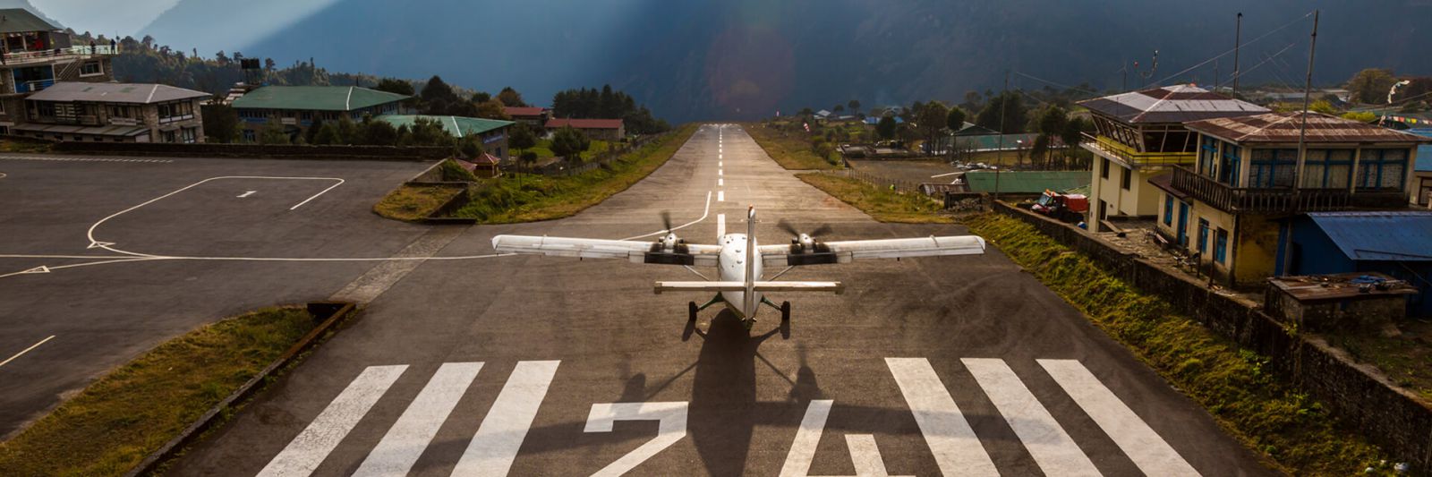 Airplane preparing for take off on Short Runway of small Airport ending at deep Mountains in Sunset Light