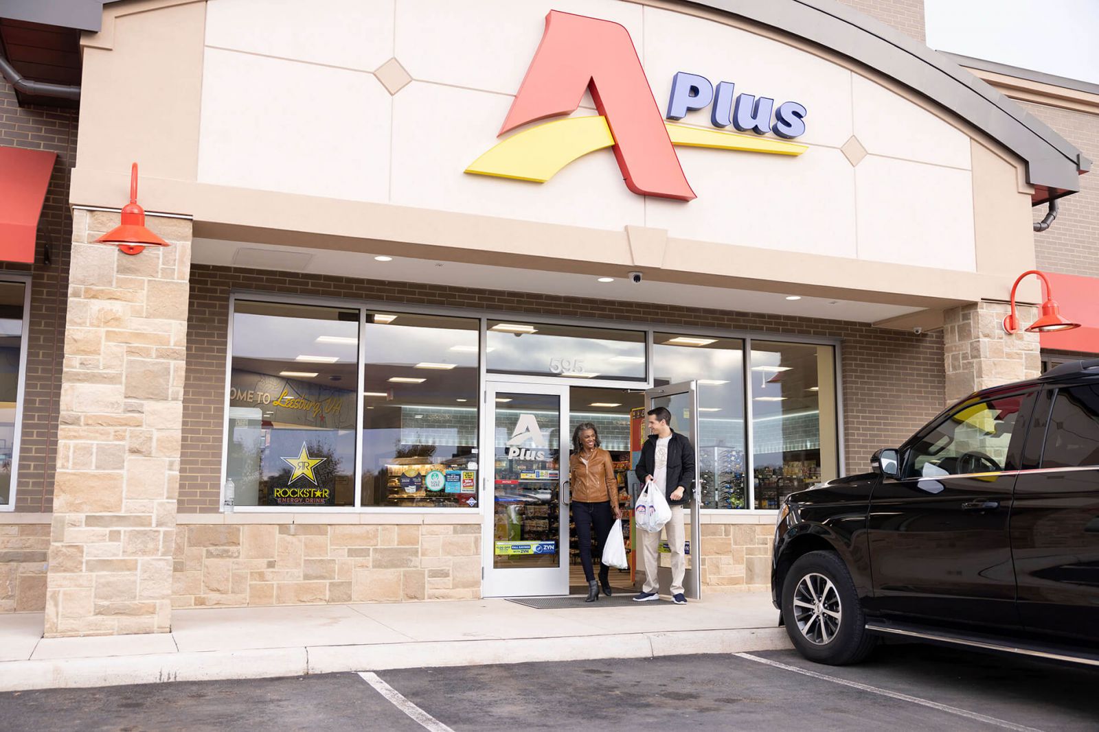 A man and a woman exiting Aplus convenience store