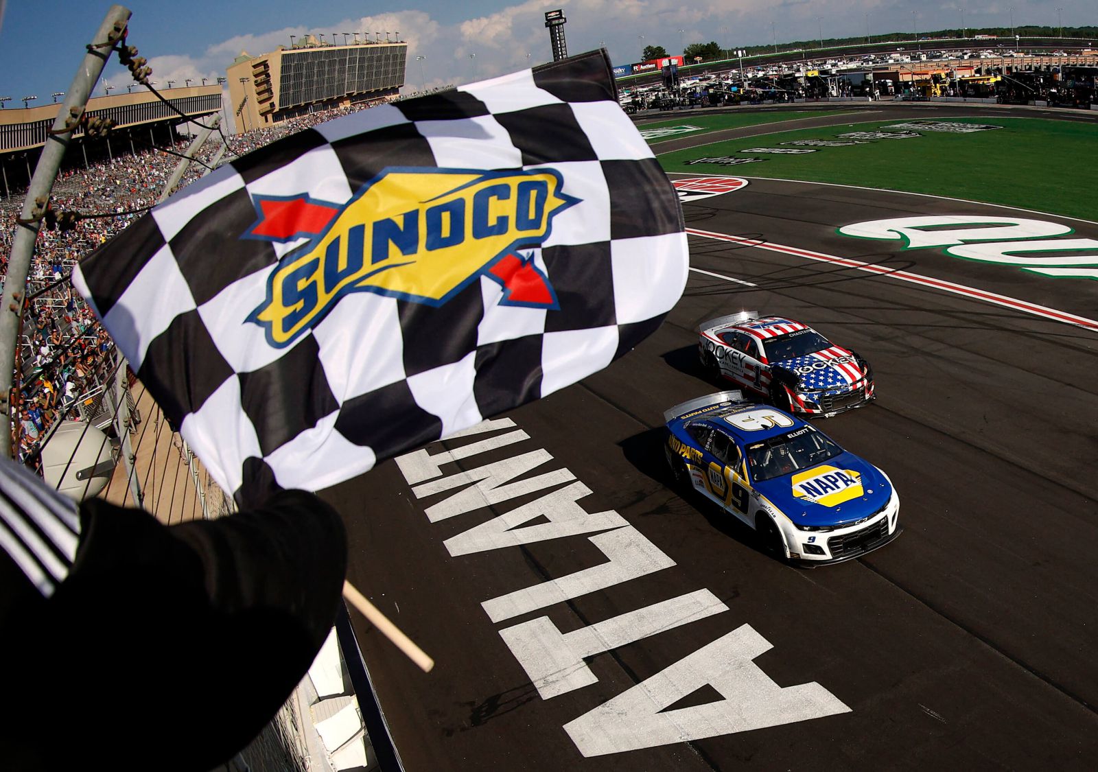 Race cars on track with Nascar official waving Sunoco flag