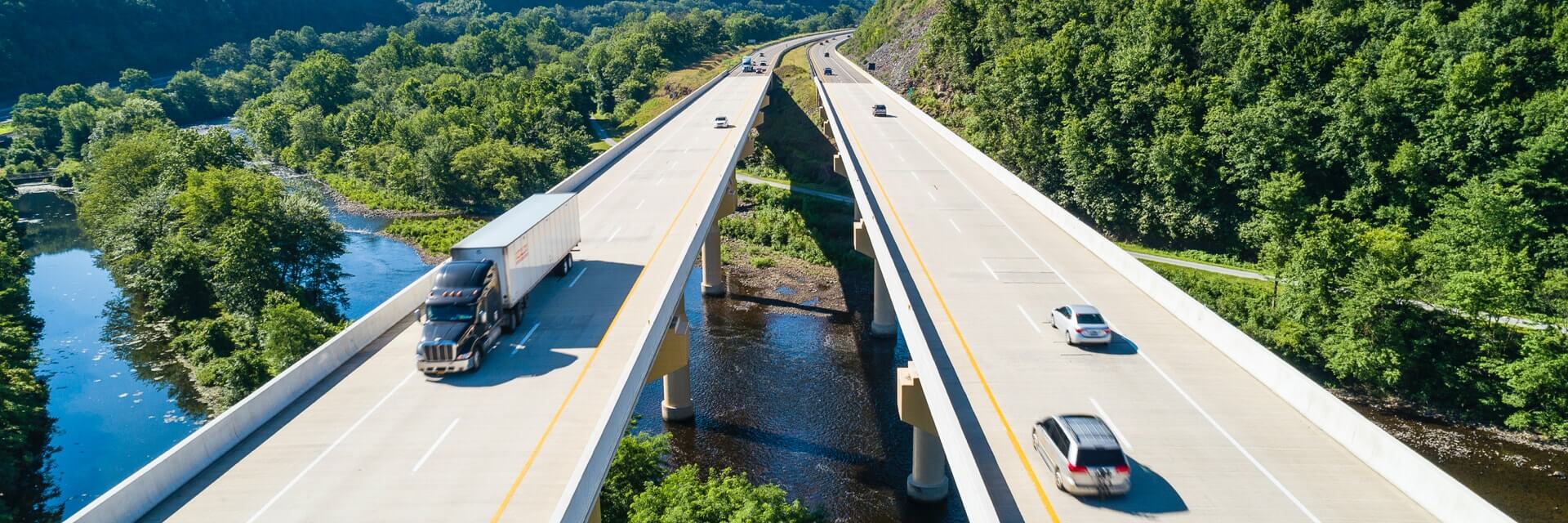 Cars and trucks on highway overpass over river