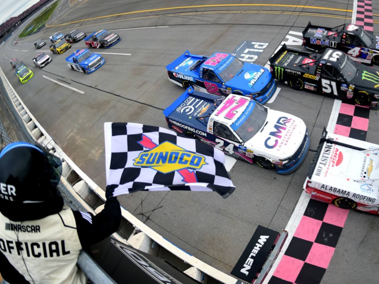 Race trucks on track with Nascar official waving Sunoco flag